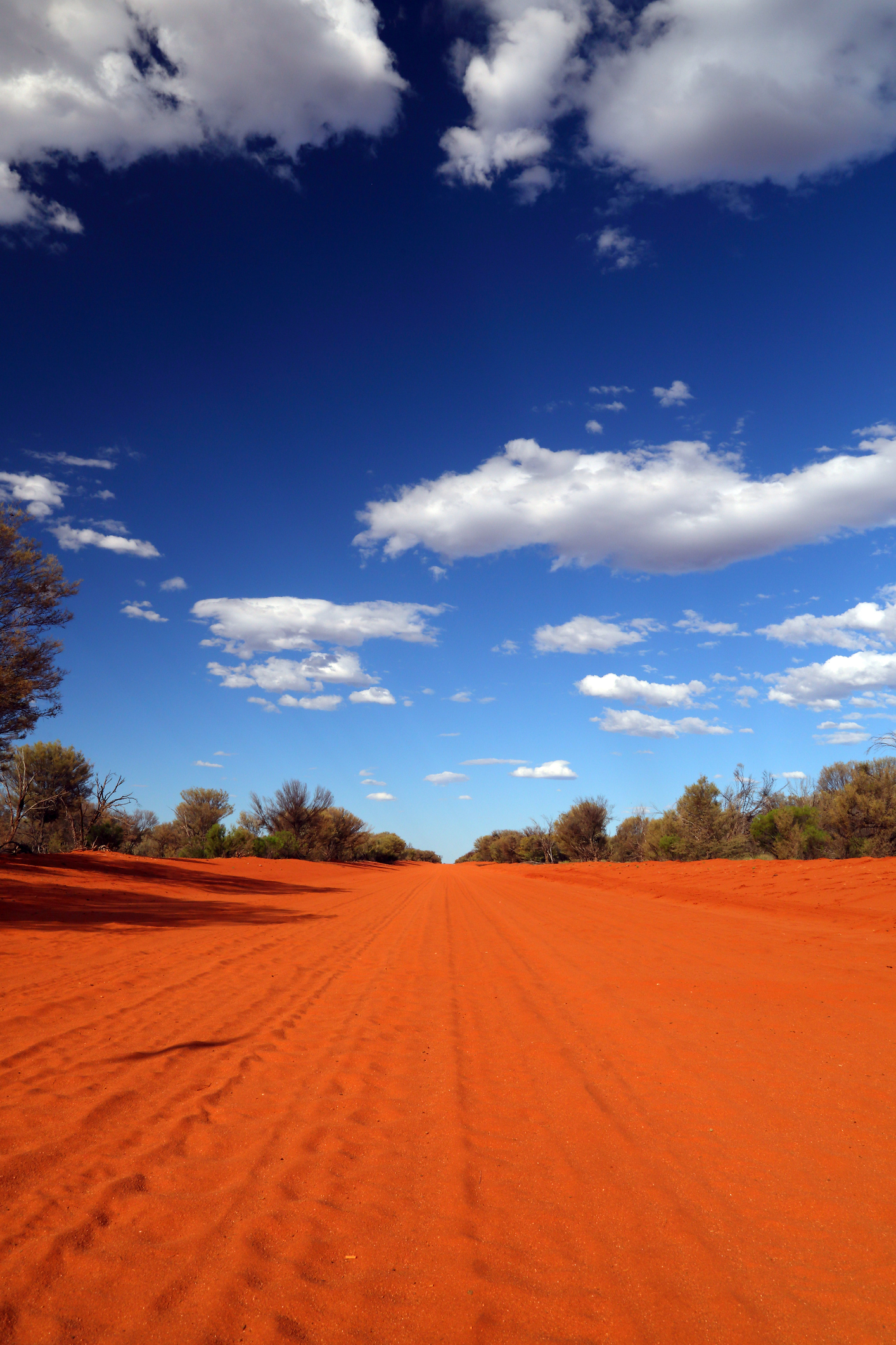 Red dirt road running to the horizon under open sky in outback Australia
